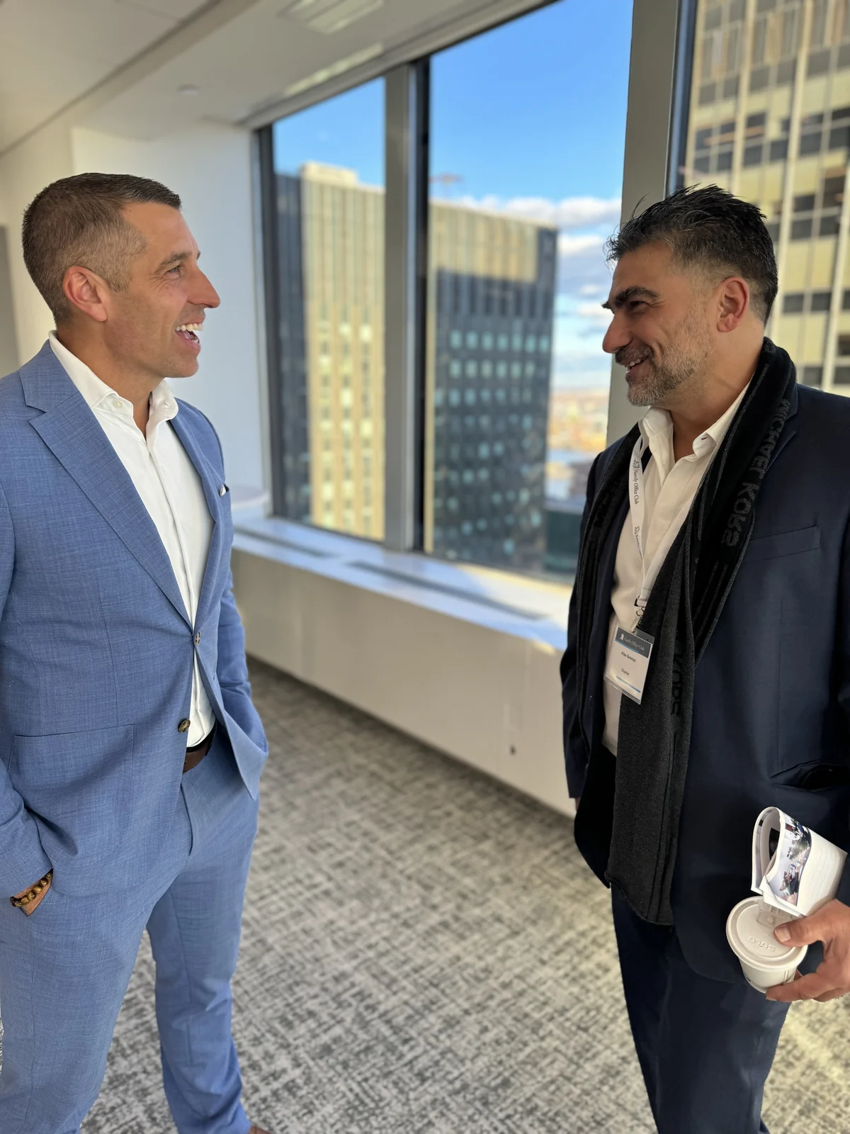 Two attendees talking by the windows at a Family Office Club event